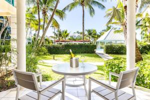 un tavolo e sedie su un patio con palme di 1 Bdrm Pool Garden View at The Yacht Club D3 a Providenciales