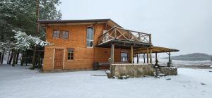 a wooden cabin in the snow with snow covered ground at Sodyba Pas Juzi in Alanta