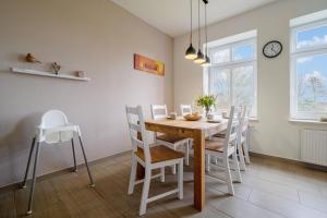 a dining room with a wooden table and white chairs at Ferienwohnung Gut Hardesby in Sörup +33 photos