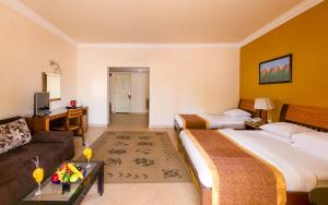 a hotel room with two beds and a couch at Xperience St. George Sharm El Sheikh in Sharm El Sheikh