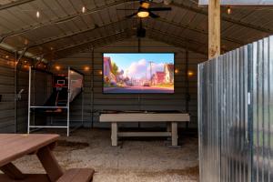 a screen in a shed with a table and a bench at Lone Star Getaway I Rec Barn I Fire Pit Nights I Movie Night Projector in Fischer