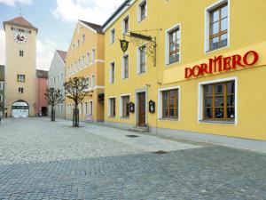 een straat met een geel gebouw met een klokkentoren bij DORMERO Hotel Kelheim in Kelheim