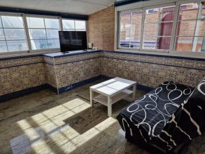 a room with a couch and a table and windows at Villa Alma in Coslada