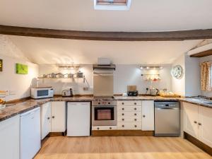 a large kitchen with white cabinets and appliances at Primrose Cottage in Shap +8 photos