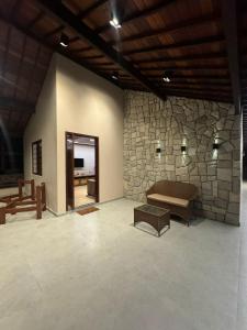 格拉瓦塔Casa Baviera 156 - Condomínio Baviera的一间配有沙发和石墙的房间