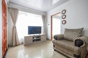 Una sala de estar con un sofá y un televisor. en Safi 1 bedroom Suite 9, en East London