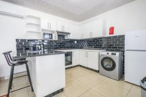 una cocina con lavadora y lavadora en Safi 1 bedroom Suite 9, en East London 3 fotos más