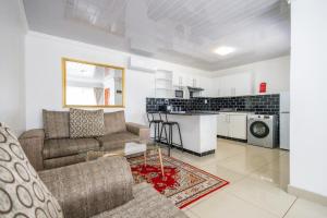 Una sala de estar con un sofá y una cocina. en Safi 1 bedroom Suite 9, en East London