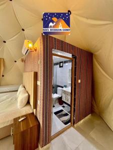 Habitación con tienda de campaña, cama y espejo en NAEL BEDOUIN lUXURY CAMP, en Wadi Rum