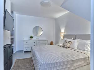 een witte slaapkamer met een bed en een spiegel bij Paros Iconic Apartments in Kampos Paros