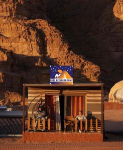 un hombre sentado en una pequeña casa en un desierto en NAEL BEDOUIN lUXURY CAMP, en Wadi Rum
