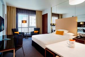 a hotel room with two beds and a desk at Centro Capital Doha - By Rotana in Doha