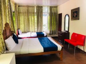 a bedroom with two beds and a red chair at Ghala Homestay in Anachal +24 photos
