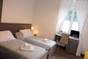 a bedroom with two beds and a desk and a window at ALBERGO LOCANDA DIANA in Genoa