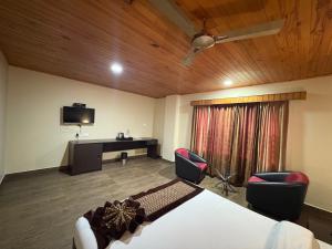 Habitación con 1 cama, 2 sillas y TV. en Hotel mmr manor&spa, en Gangtok