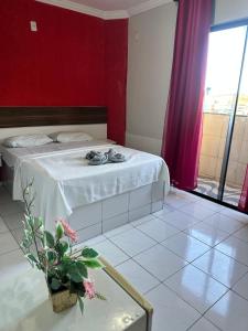 a bedroom with a bed with a red wall at Hotel Brasília Park in Novo Gama