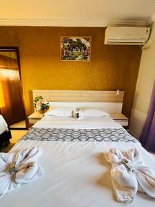 a bedroom with a white bed with towels on it at Hotel Brasília Park in Novo Gama