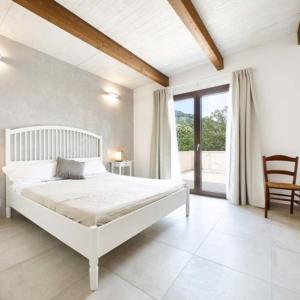 a white bedroom with a bed and a large window at Villapiana Country House in Pellezzano