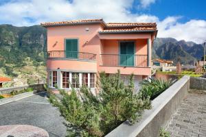 a pink house with a balcony and mountains in the background at Cristina Grand in São Vicente