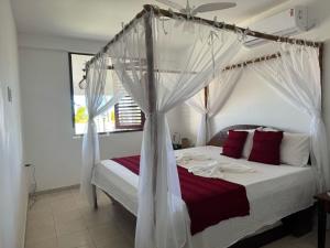 ein Schlafzimmer mit einem Himmelbett mit roten und weißen Kissen in der Unterkunft Casa Pé na Areia in São José da Coroa Grande + 92 Fotos