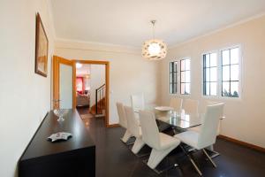 a dining room with a glass table and white chairs at Cristina Grand in São Vicente