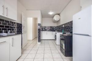 a kitchen with white cabinets and black tiles on the walls at Safi Luxury Apartment 2 in East London