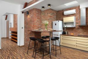 a kitchen with a brick wall and a bar with stools at Old Town Apartment Spilberk by goodnite cz in Brno