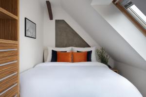 sypialnia z białym łóżkiem z pomarańczowymi poduszkami w obiekcie Old Town Apartment Spilberk by Goodnite cz w mieście Brno