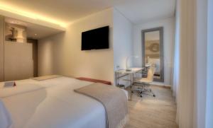 Un dormitorio con una cama, un escritorio y un televisor. en NH Collection Porto Batalha, en Oporto