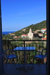 una mesa y sillas en un balcón con vistas al océano en Hotel Cyrnos, en Cargèse