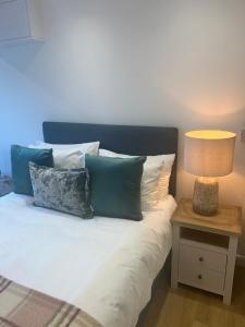 a bed with pillows and a lamp on a table at The Little Fern in Oxford