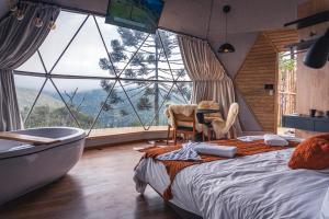 a bedroom with a tub and a bed with a view at Le Refuge Urubici in Urubici