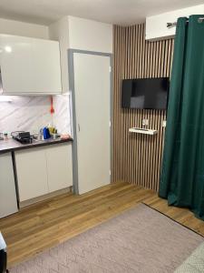 a kitchen with white cabinets and a flat screen tv at Magnifique studio en bord de mer vue montagne in Saint-Cyprien