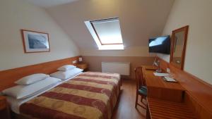 sypialnia z łóżkiem, biurkiem i telewizorem w obiekcie Hotel Baross w Győr