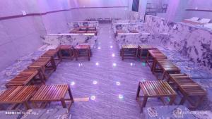 an empty room with wooden tables and benches at Hotel Greenland Inn Hampi in Hampi