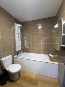 a bathroom with a toilet and a tub and a sink at Mega Value Stay - 7 Beds, Keyless Entry, City 5 min walk BY PROPERTY PROMISE in Cardiff +9 photos