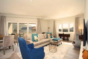 een woonkamer met een bank, stoelen en een piano bij Comfort & Style apartment 200m to beach with parking in Kaapstad