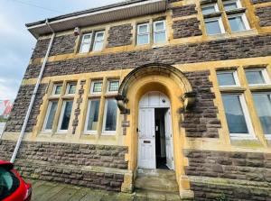 a brick building with a white door and a car at Stacey's 4 Bedroom House in Pontypool in Pontypool