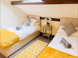 a bedroom with two beds and a table with a rug at Stacey's 4 Bedroom House in Pontypool in Pontypool