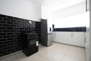Una cocina con azulejos blancos y negros y una estufa. en Safi Luxury Apartment 6 - 2 bedroom, en East London