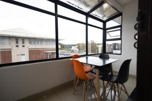 una mesa y sillas en una habitación con ventanas grandes en Safi Luxury Apartment 6 - 2 bedroom, en East London