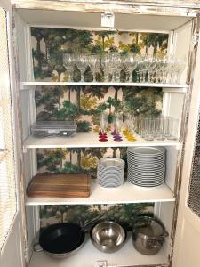 a pantry with glasses and plates on a shelf at Tissianna Villa Confort de Grand Anse in Petite Île