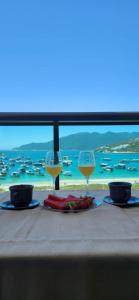 a table with two glasses of wine and a view of the ocean at Residence Club Praia Dos Anjos vista al mar in Arraial do Cabo