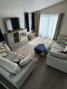 a living room with two couches and a tv at Yellow Bush Lodge in Haven Street