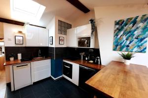 a kitchen with white cabinets and a wooden table at Grand appartement proche métro avec place de parking in Lyon
