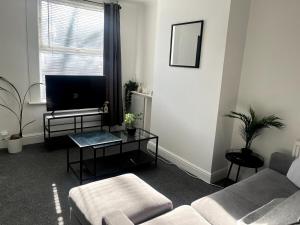 a living room with a couch and a flat screen tv at Cosy 2-Bed Home - Central Location Near Town & Train Station in Dartford +6 photos