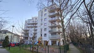 a tall white building with a playground in front of it at RIVERS Apartment in Kołobrzeg