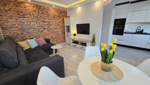 a living room with a couch and a brick wall at RIVERS Apartment in Kołobrzeg