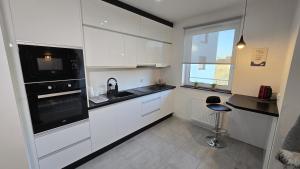 a kitchen with white cabinets and a black appliance at RIVERS Apartment in Kołobrzeg