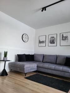 a living room with a couch and a clock on the wall at Apartament 150 Zaspa VVita z ogrodem i tarasem in Gdańsk
